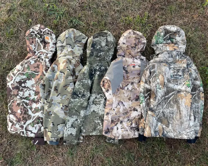 Womens hunting jackets from Sitka, KUIU, DSG, and more laid out on grass