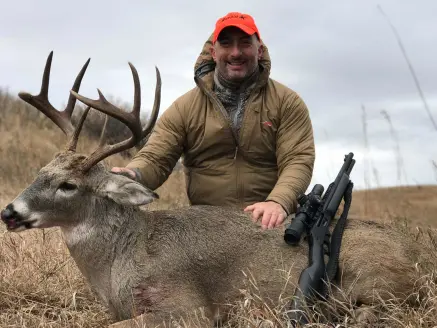 Hunter kneeling behind a deer.