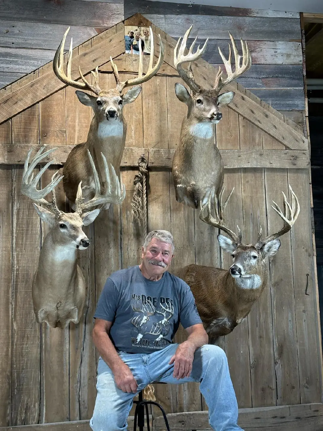Well known deer hunter Sam Collora poses with mounts of his four biggest whitetail bucks.