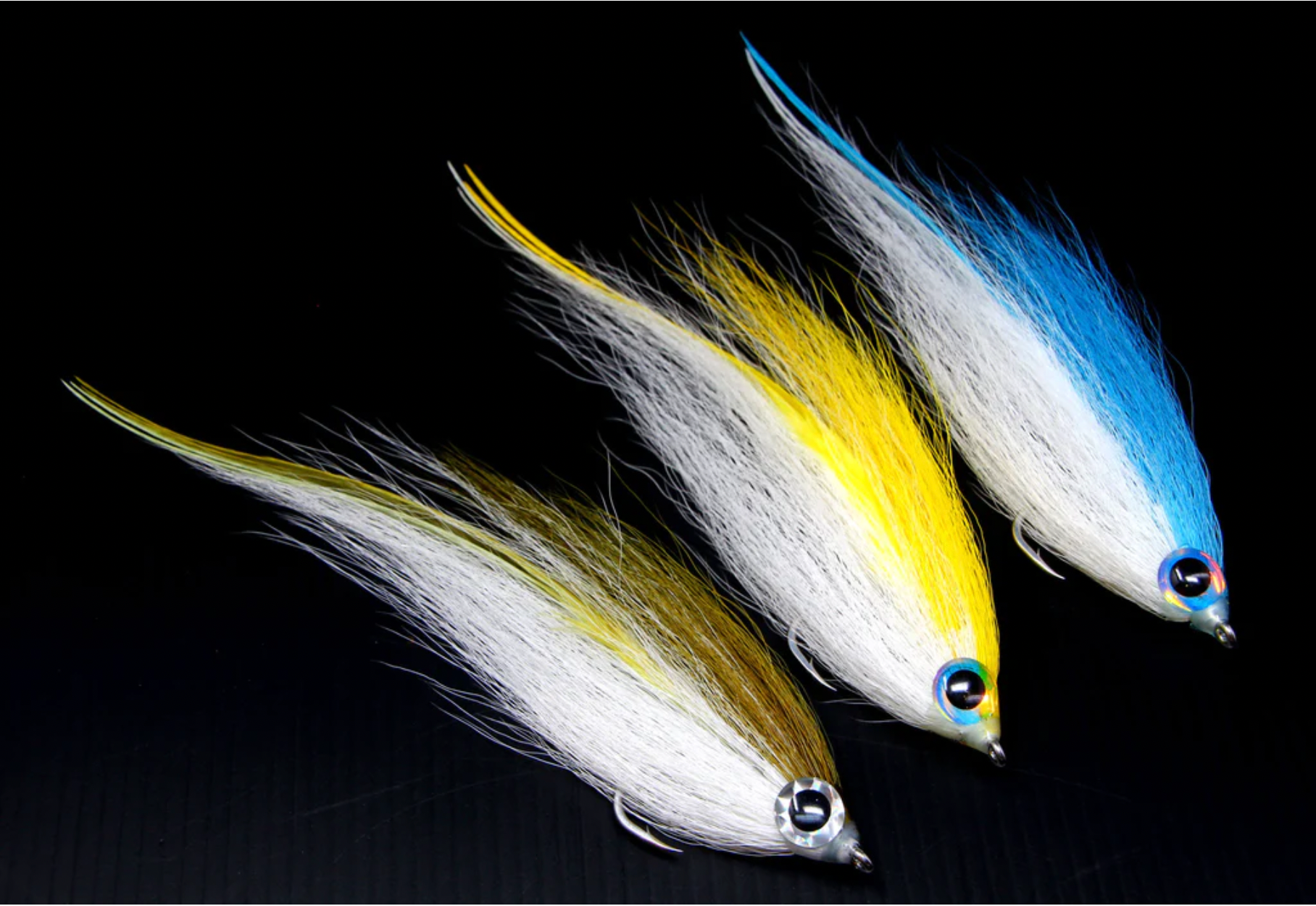 Three Hollow Fleye fly patterns on a black background