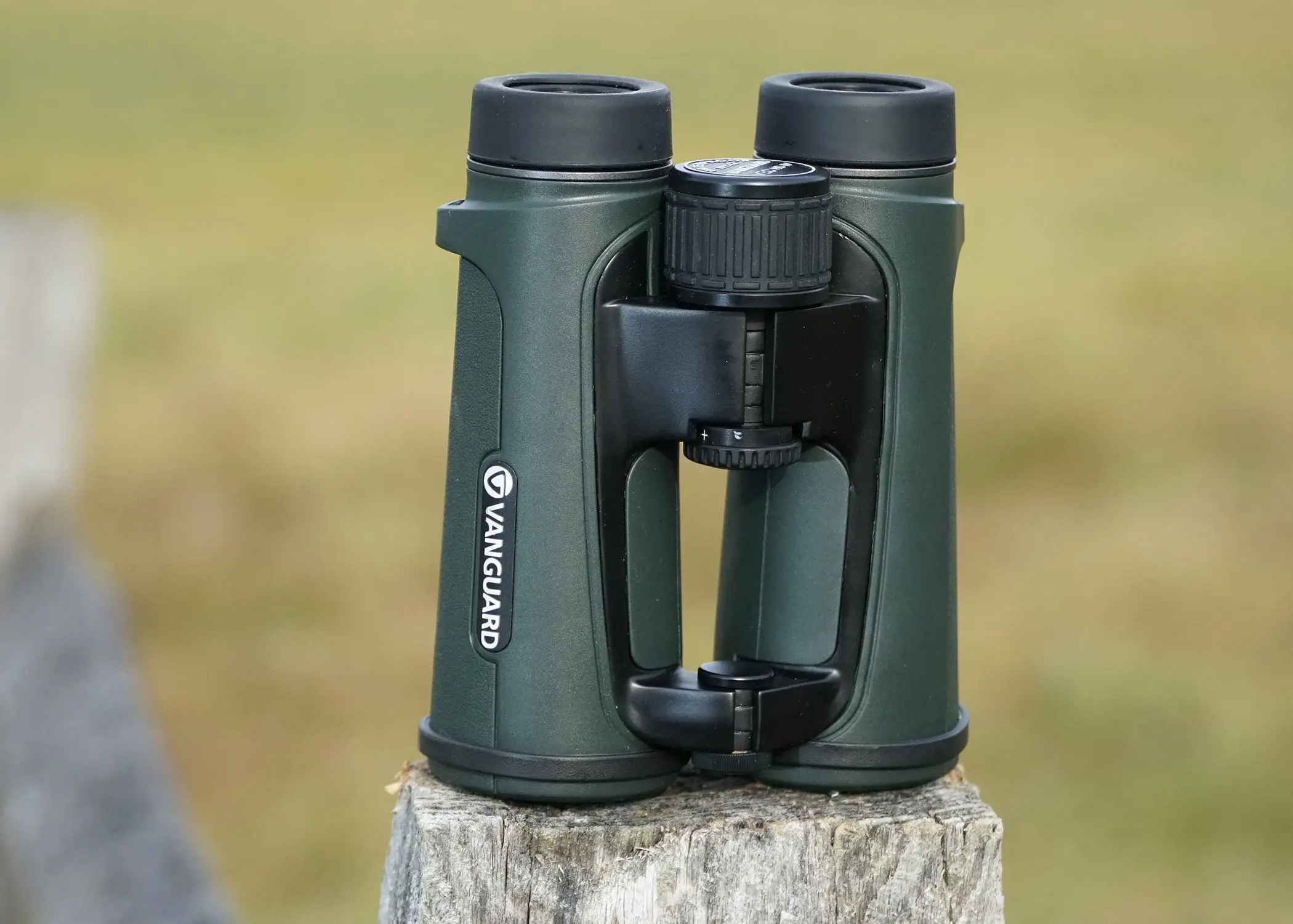 Vanguard 10x42 binocular sitting on fence post with field in background