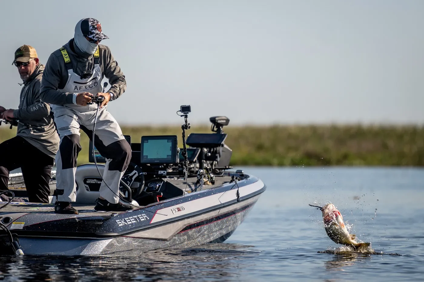 Pro bass angler Scott Martin reels in a big largemouth bass at the edge of his bass boat