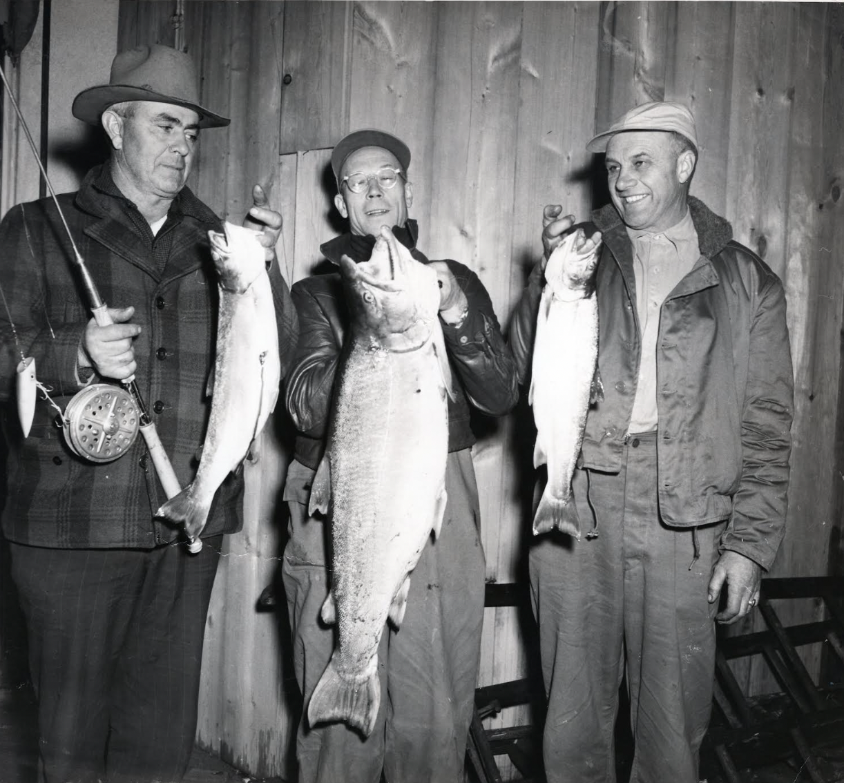 Three men holding fish.