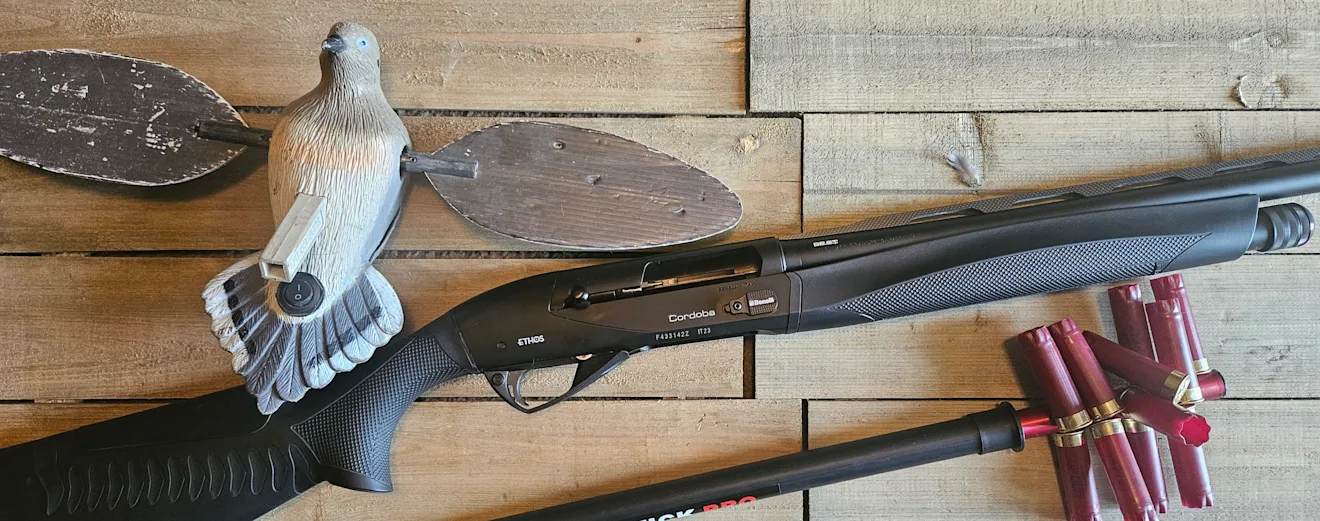 The new Benelli Ethos Cordoba A.I. BE.S.T. on a wood surface with emtpy shotgun shells and a dove decoy.