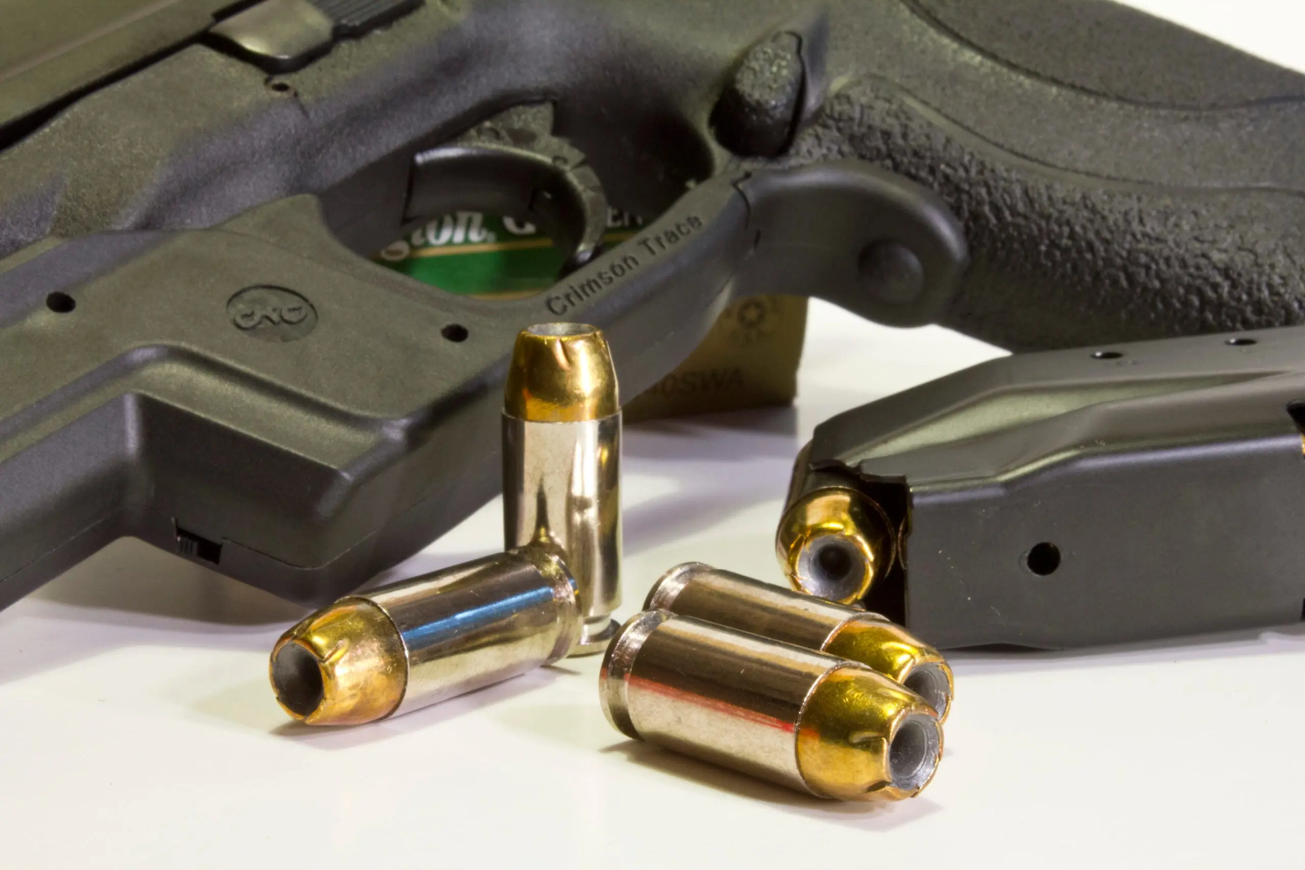 40 S&amp;W cartridge lying near a pistol and magazine on white background