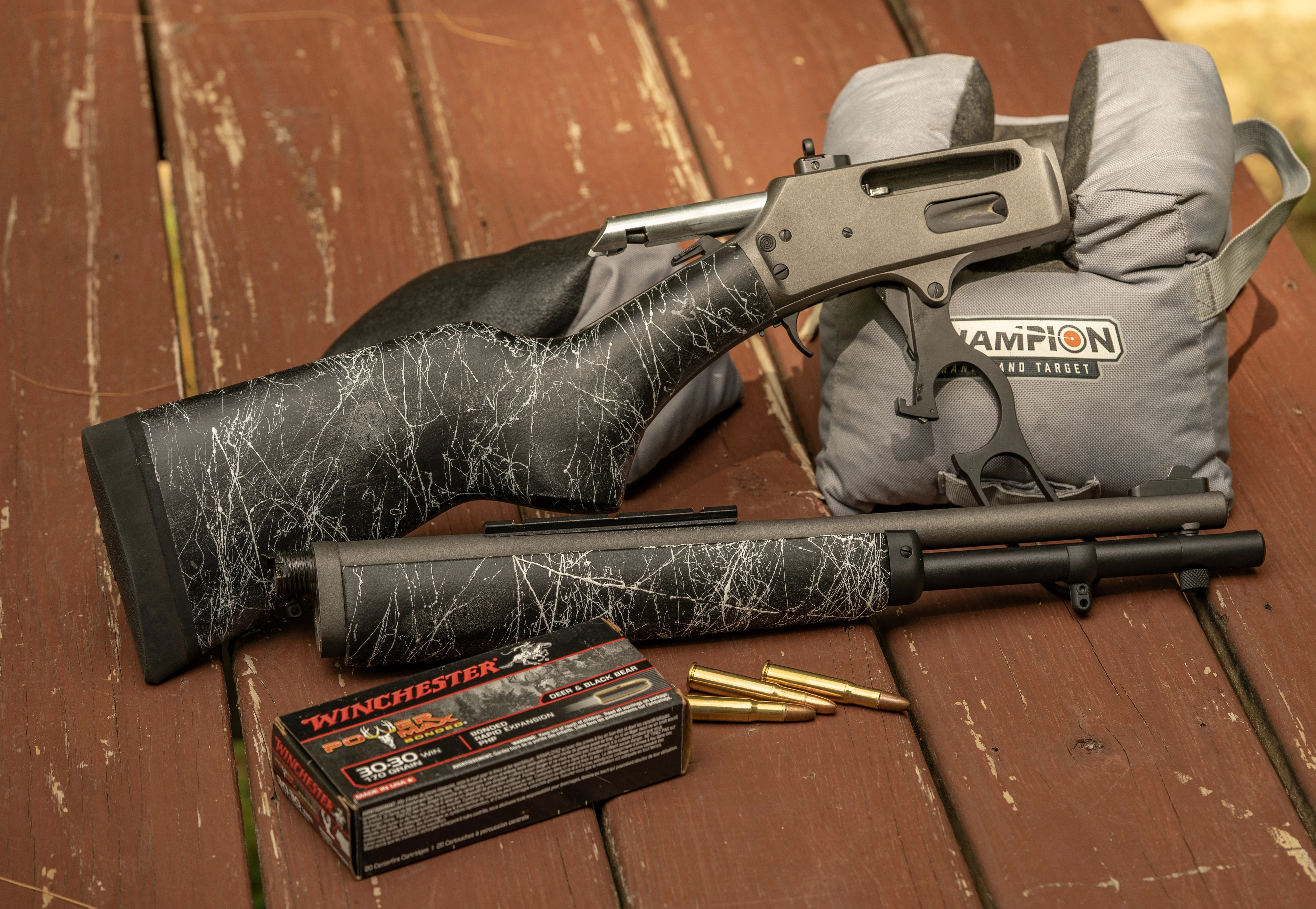 A Dove Custom Appalachian Scout rifle taken down and resting on a bench with sandbags and ammo. 