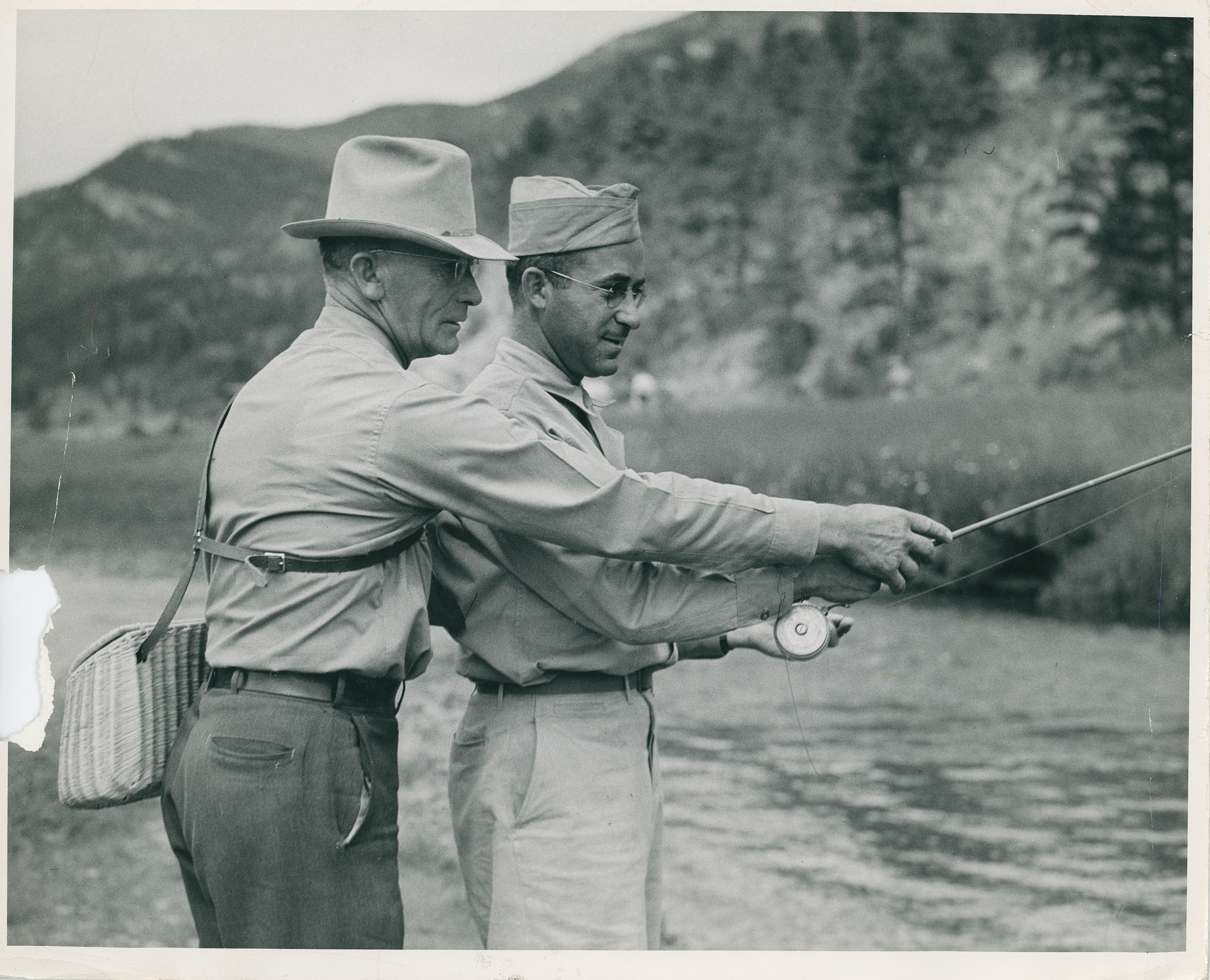 A man in a cowboy had teaches an air force veteran how to cast a fly fishing rod