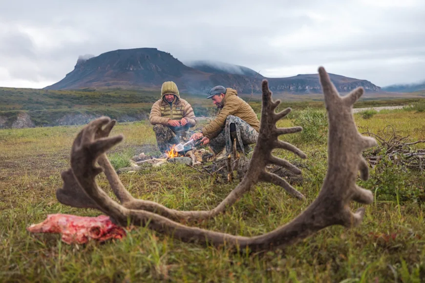Hunters cook freshly-harvested caribou over an open flame in Alaska's Brooks Range.