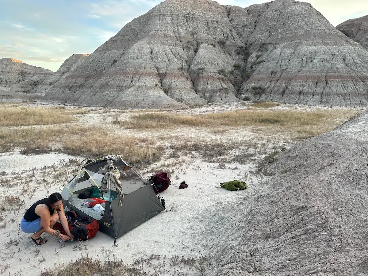 Woman wearing Xero Shoes Z Trail EV while setting up tent at desert campsite