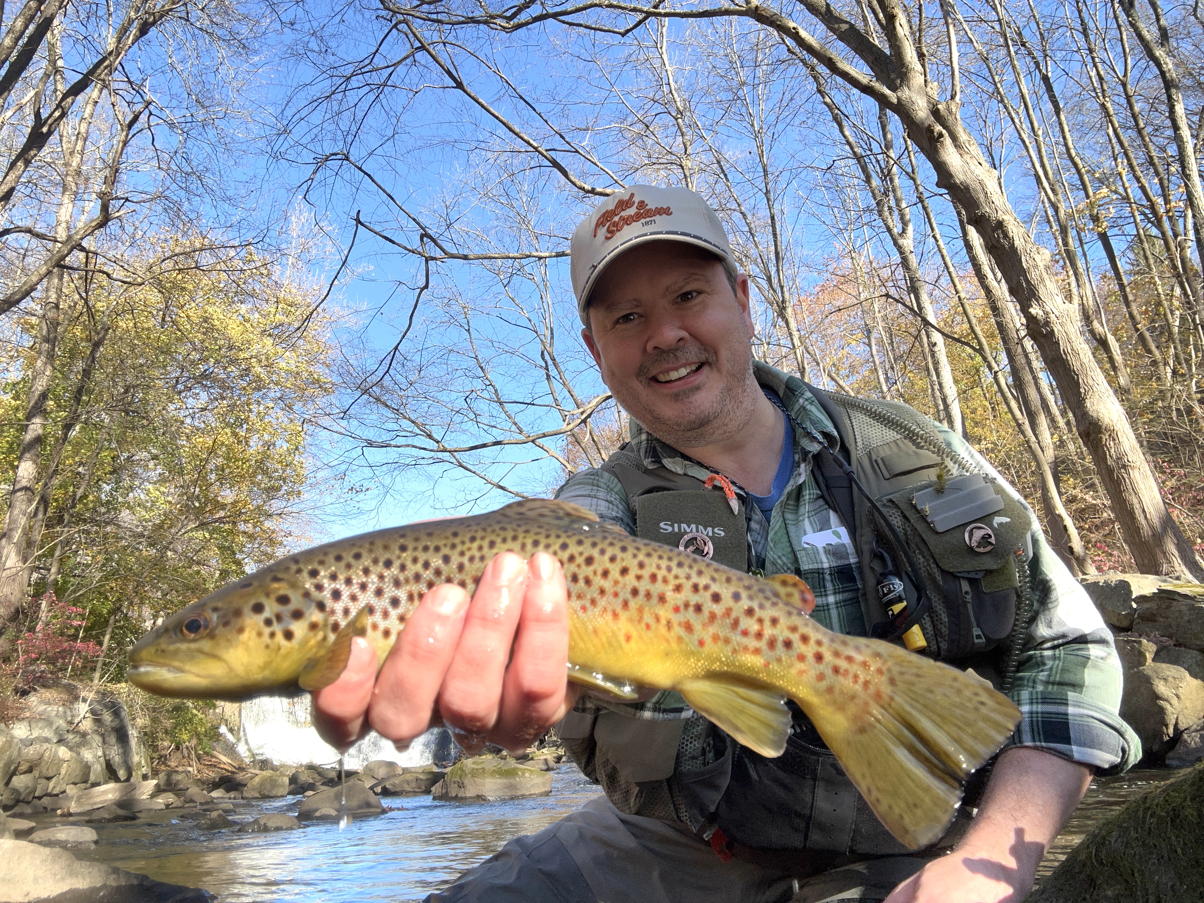 a fly fisherman holds a brown trout
