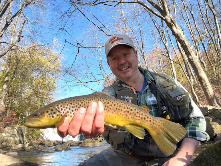 a fly fisherman holds a brown trout