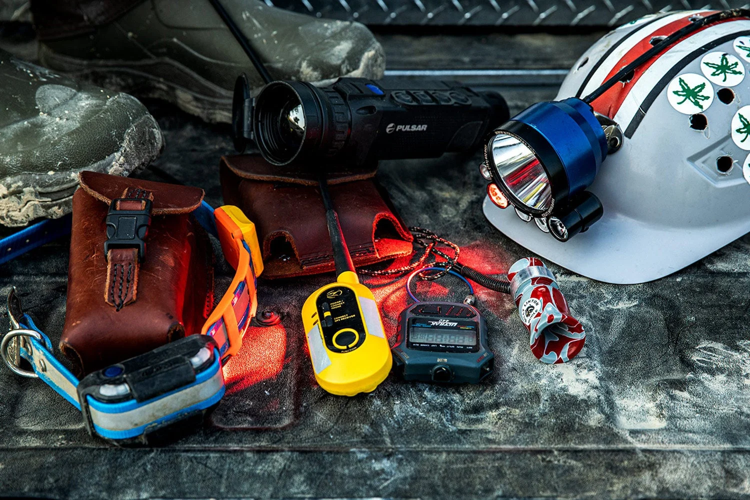 collection of raccoon hunting gear on truck tailgate includes helmet with lamp, gps collar, and call