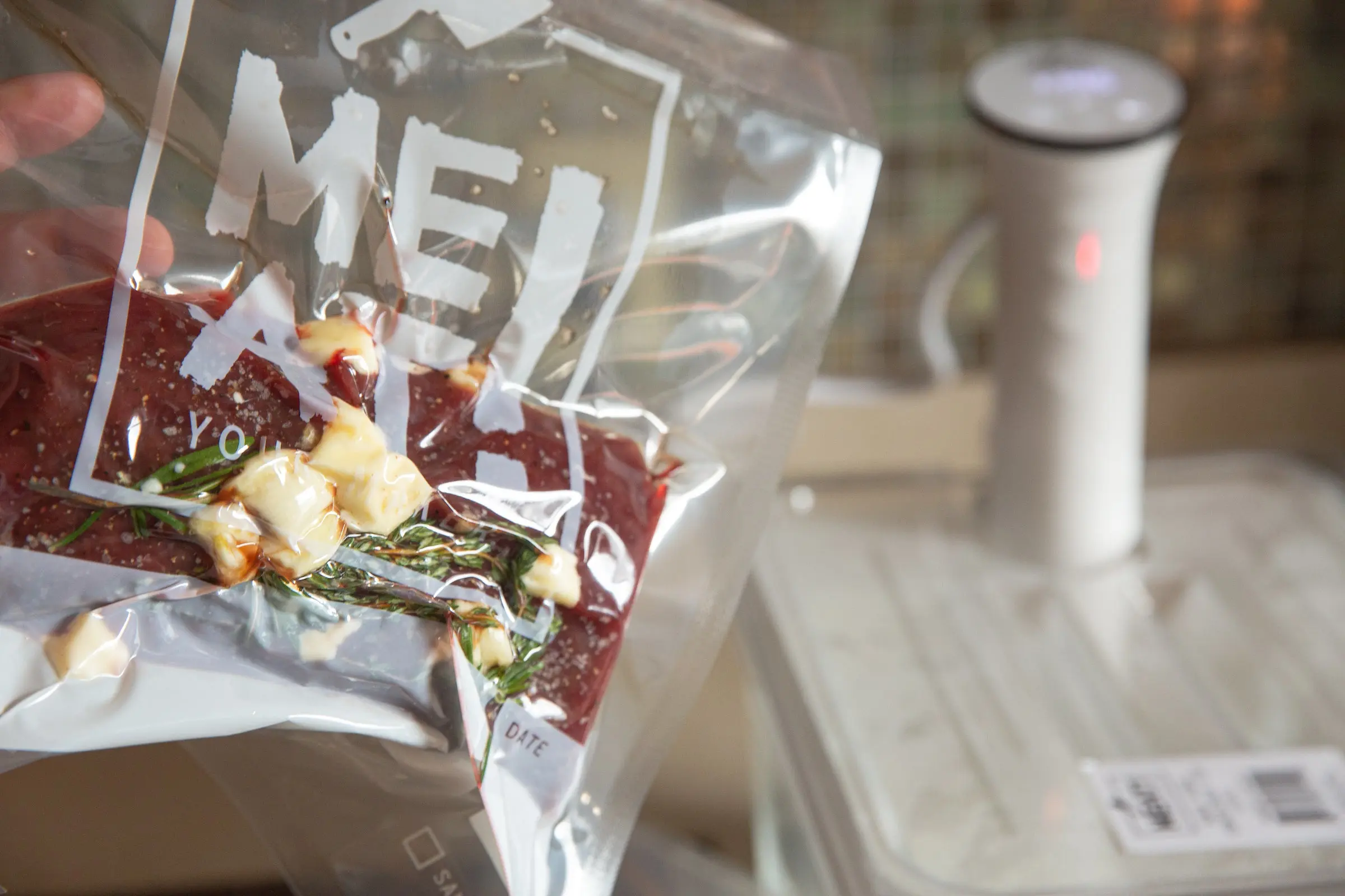 Vacuum-sealed bag of venison with herbs and garlic.