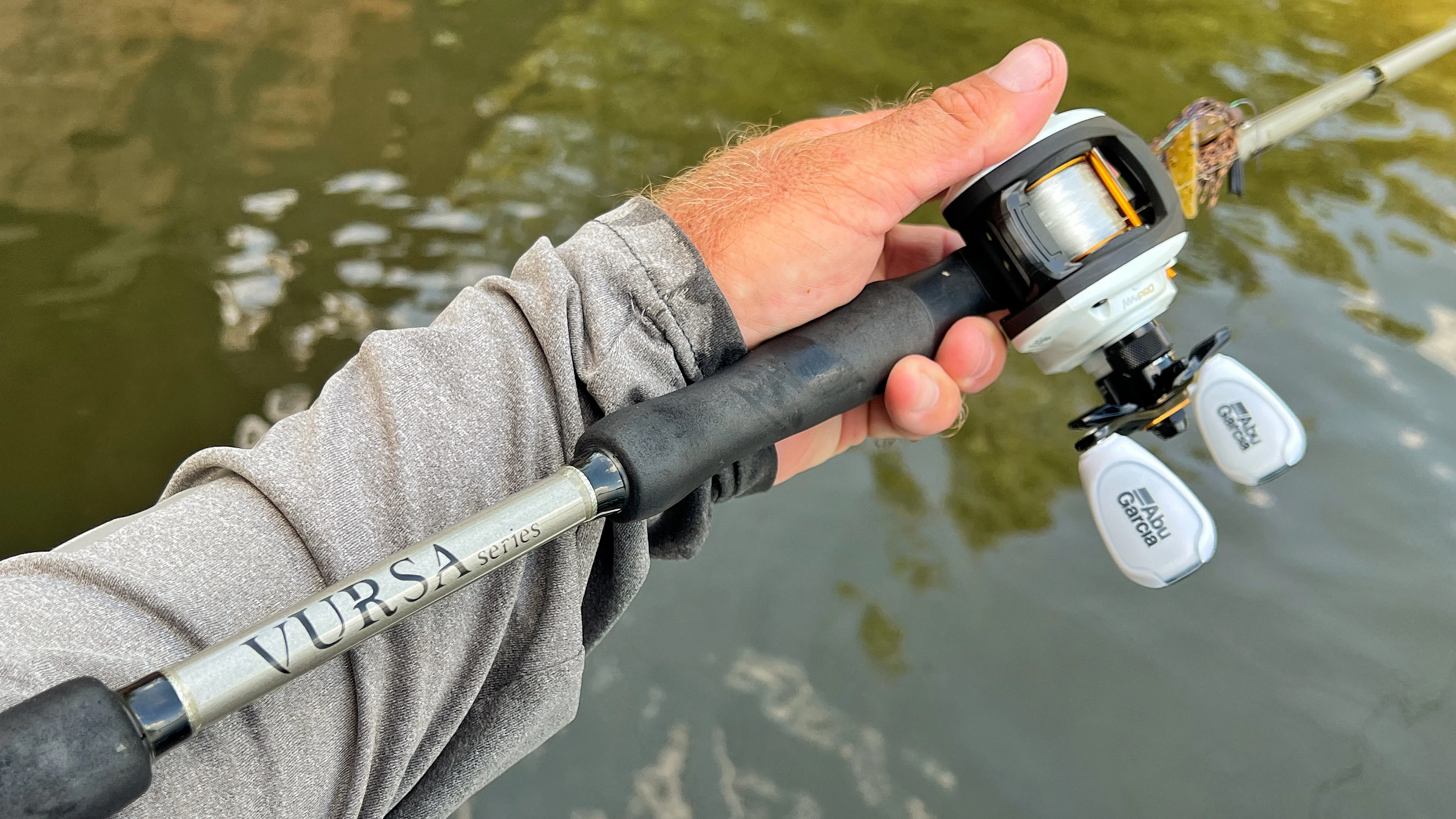 An angler's hand holding a baitcasting rod 