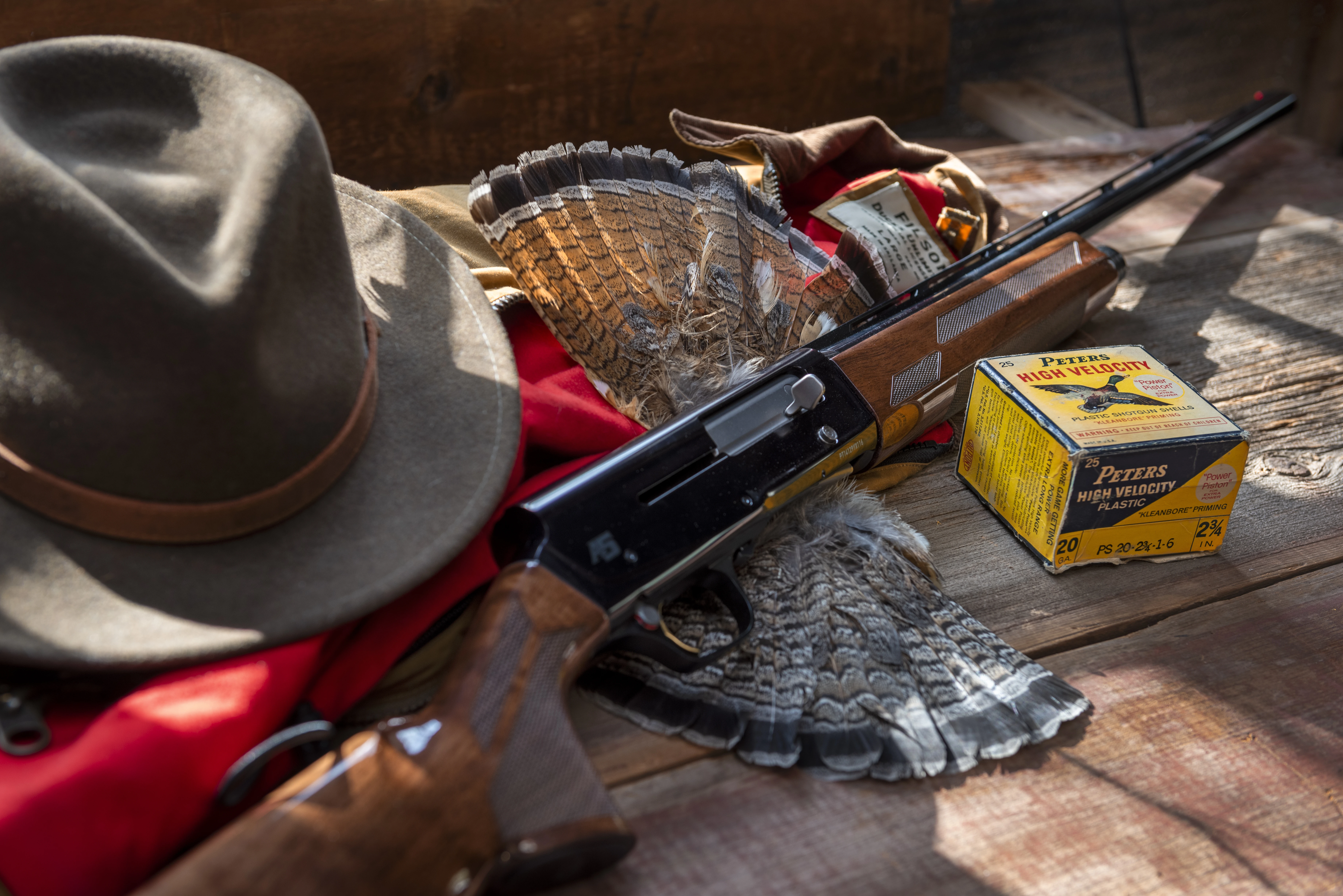 The new Browning A5 20-gauge on a table with grouse fans, shotgun shells, a hunting vest, and a hat. 