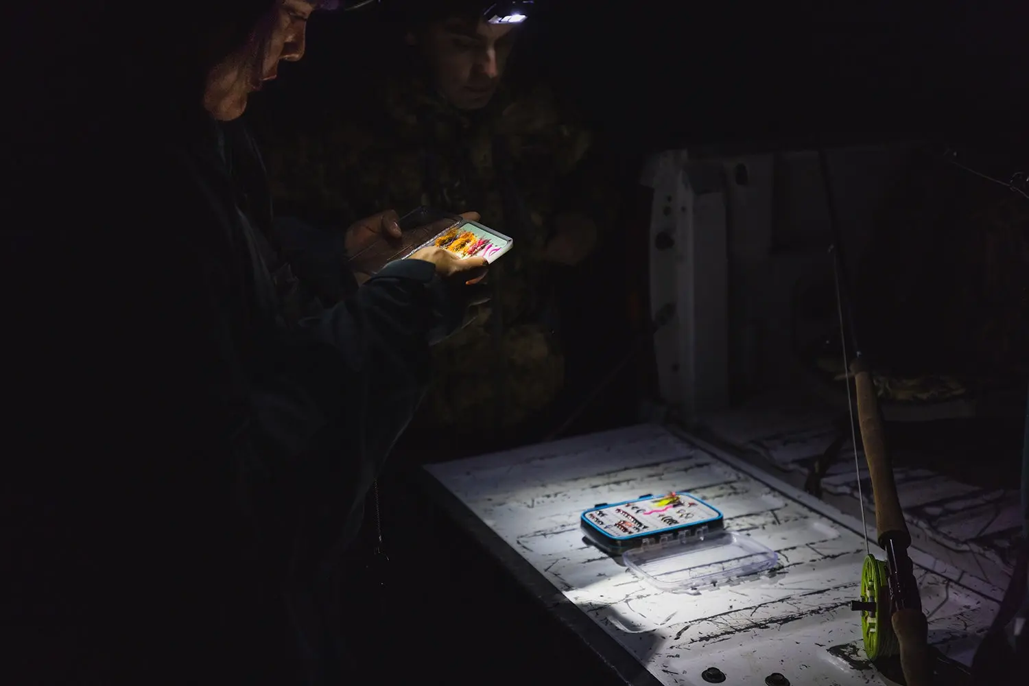 Anglers with headlamps search through fly boxes