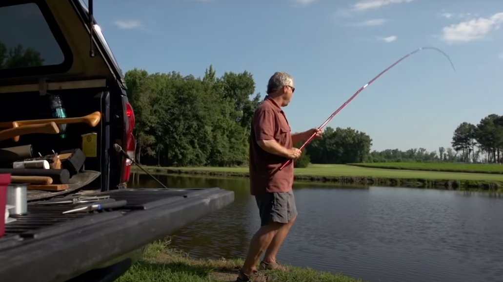 man cane pole fishing on a pond.