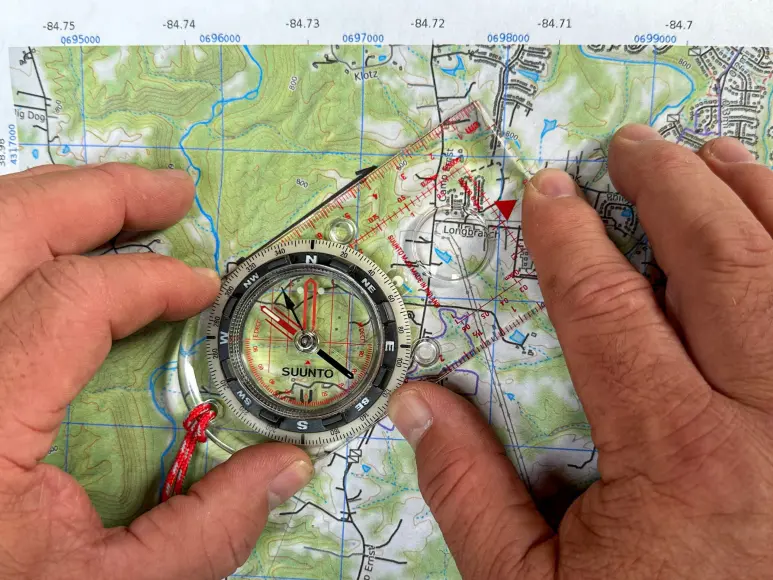 a person demonstrating how to use a compass with a map