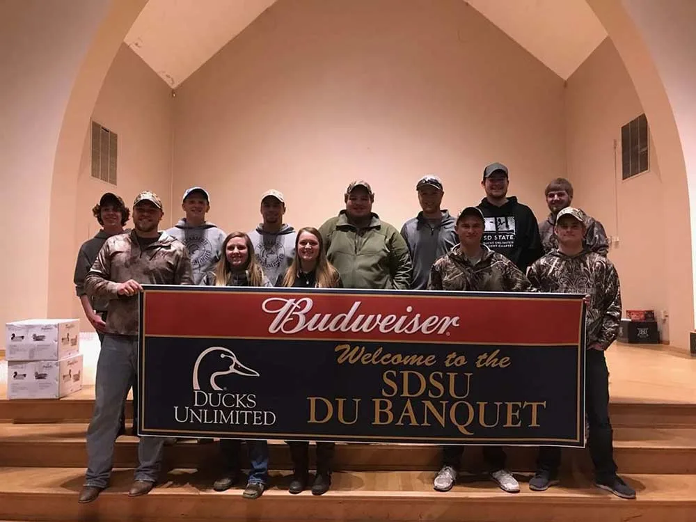 group of college hunters holding up a sign