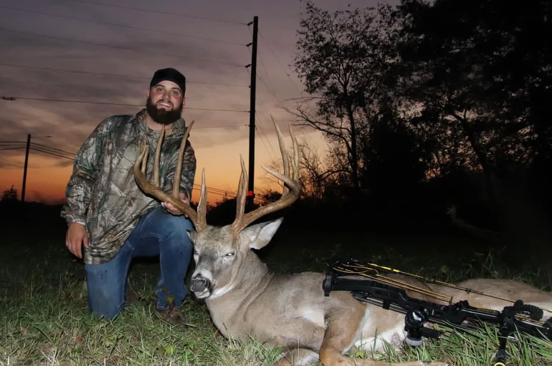 A hunter poses with a huge typical whitetail buck he took with bow. 