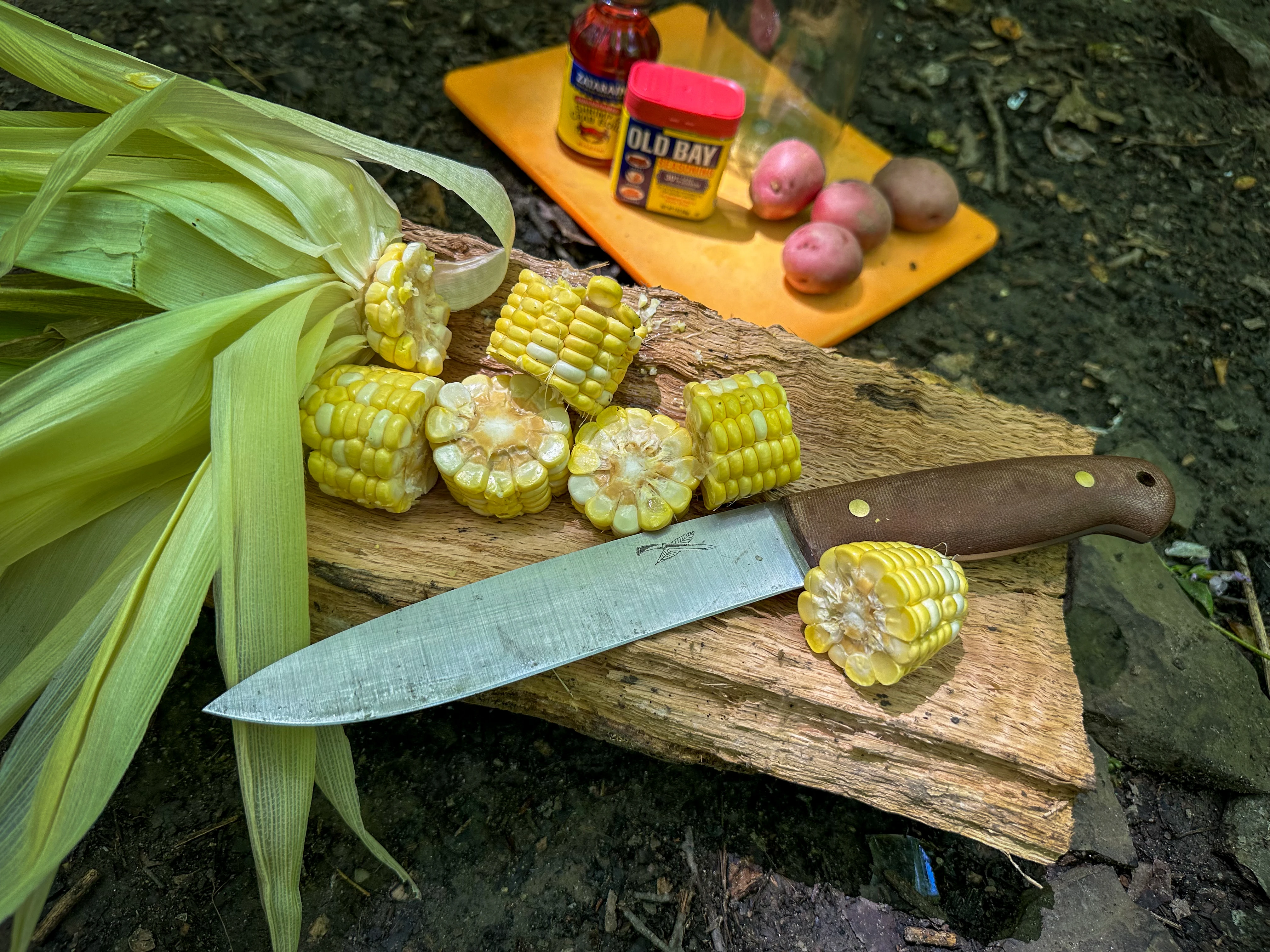 Corn cut into chunks on a board next to a large knife