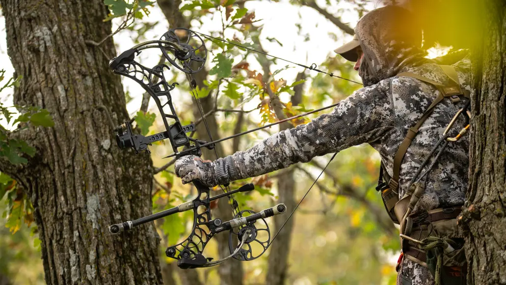 photo of.a bowhunter at full draw in a tree stand