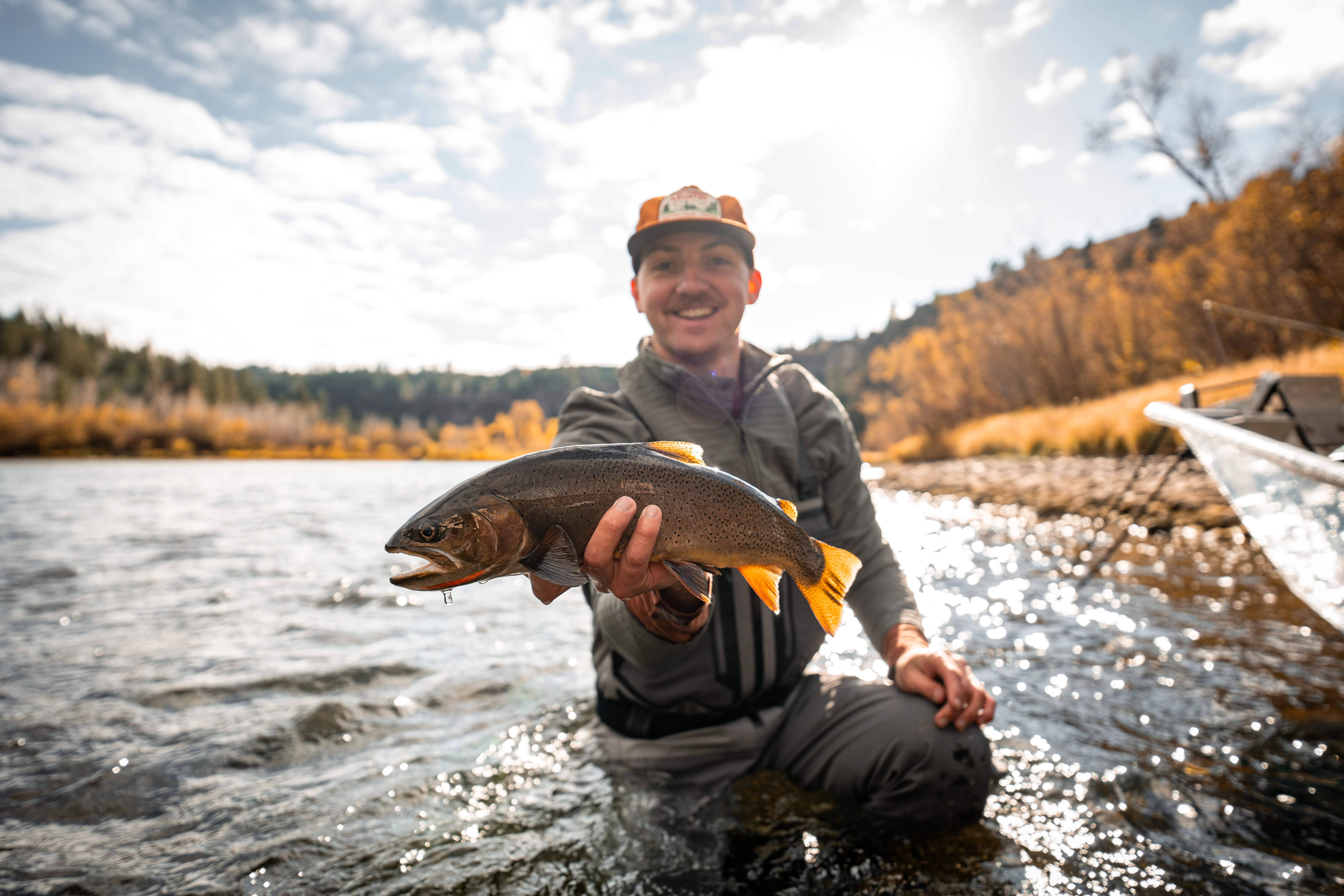 Angler holds up trout while standing in river