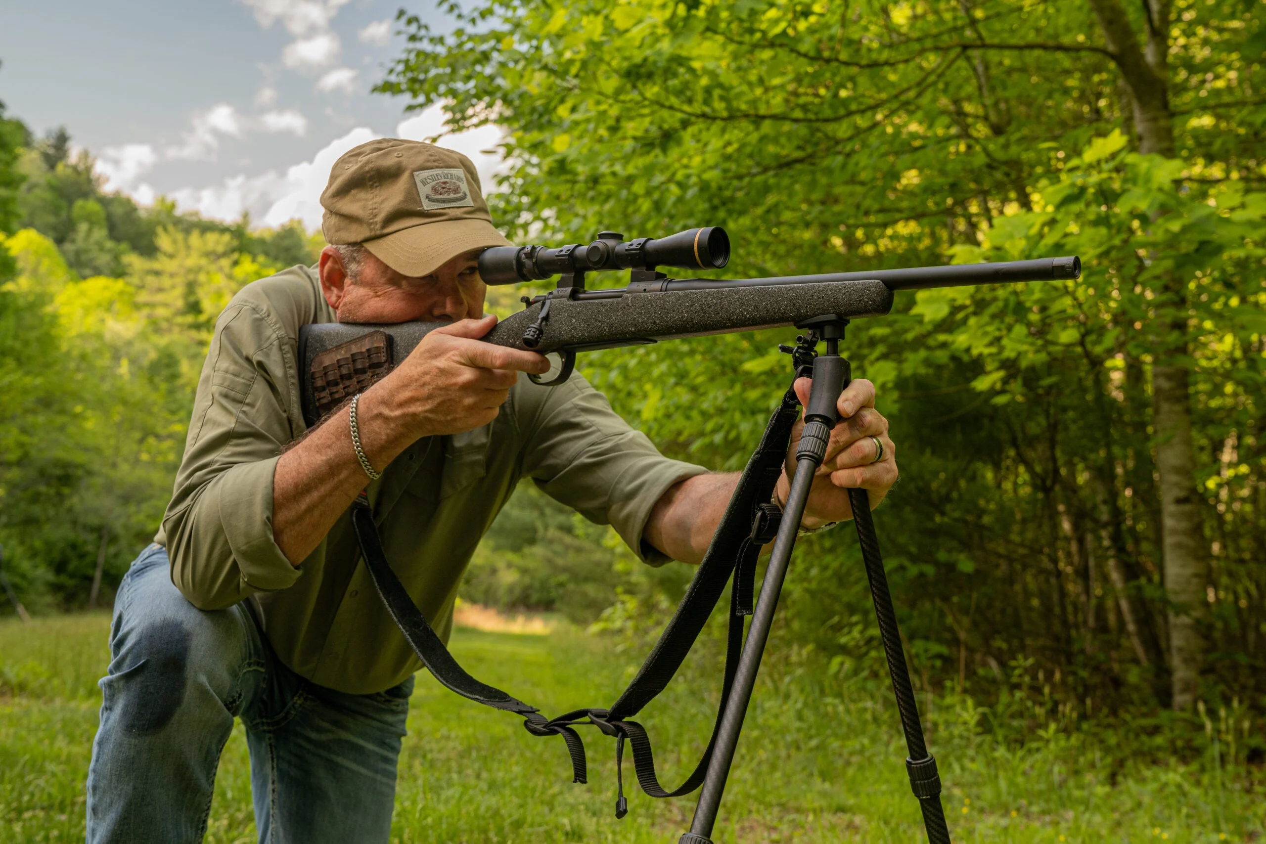 A shooter practices dry firing with a bolt-action rifle resting on a tripod.