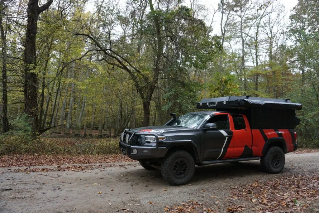 Overlanding toyota tacoma parked on a dirt road near the swamp.