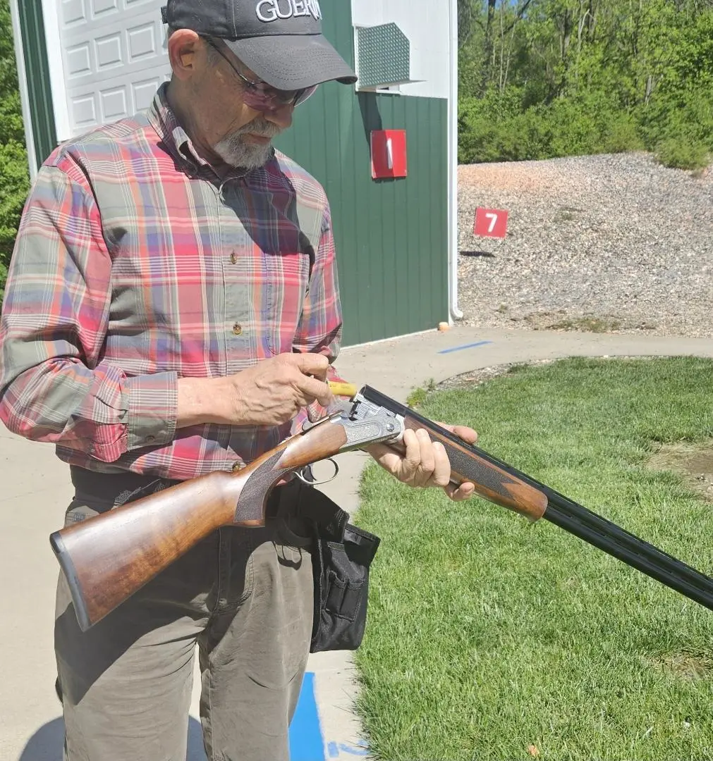 A shooter loads a Mossberg Gold Reserve 20-gauge shotgun at the skeet range.