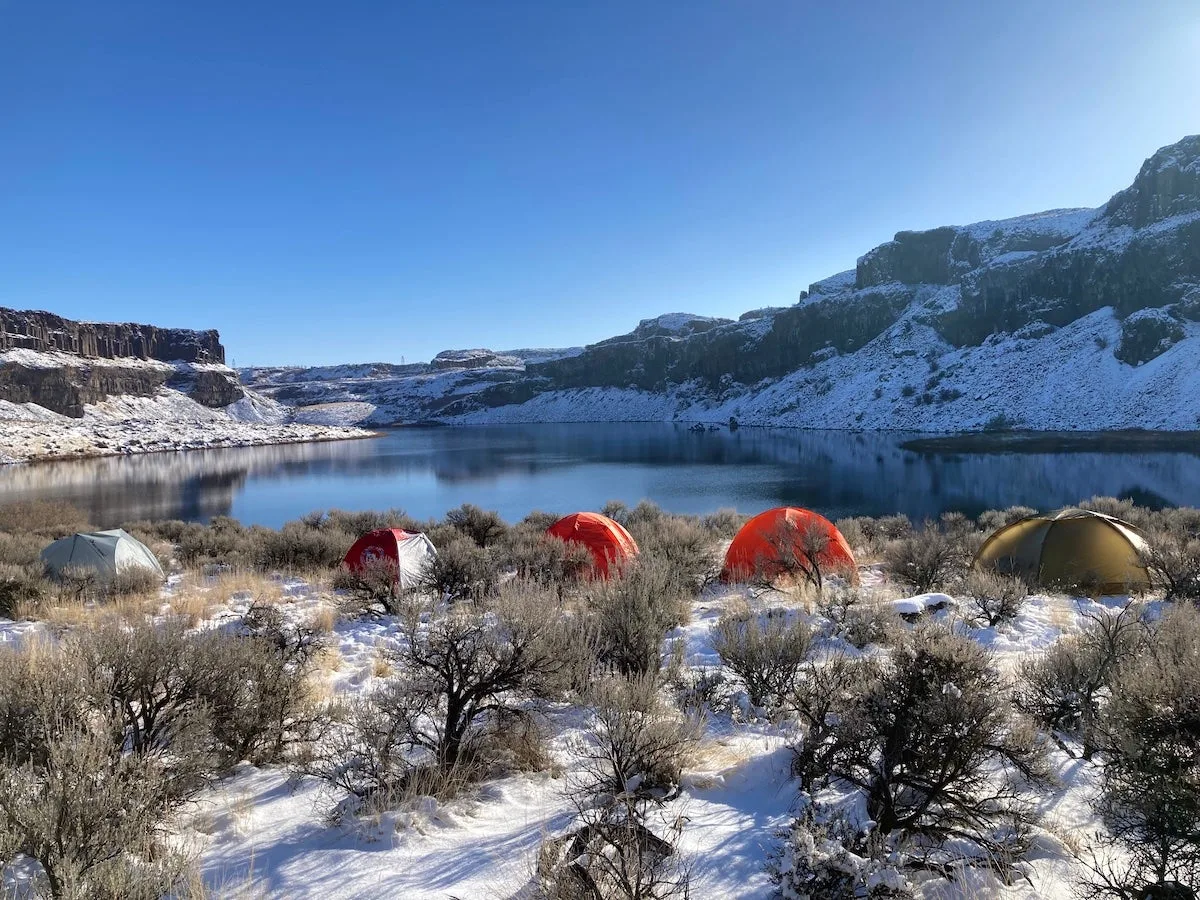 4-season tents set up in a line in front of mountainscape