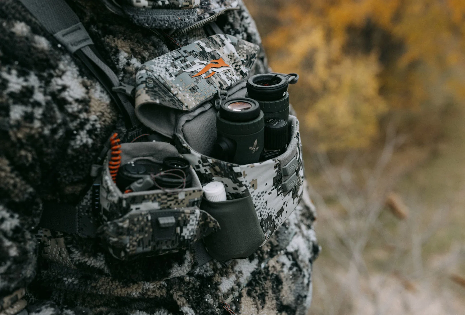 Hunter holds binos and rangefinder in Sitka binocular harness. 