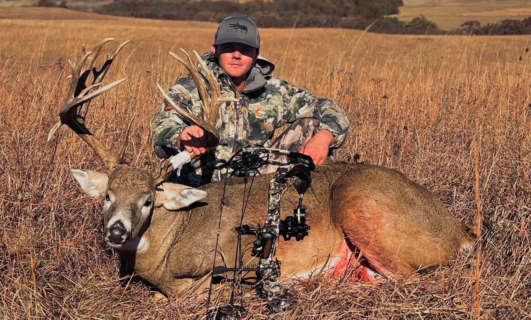 A hunter poses on the Kansas prairie with a trophy whitetail buck he took with a bow.  