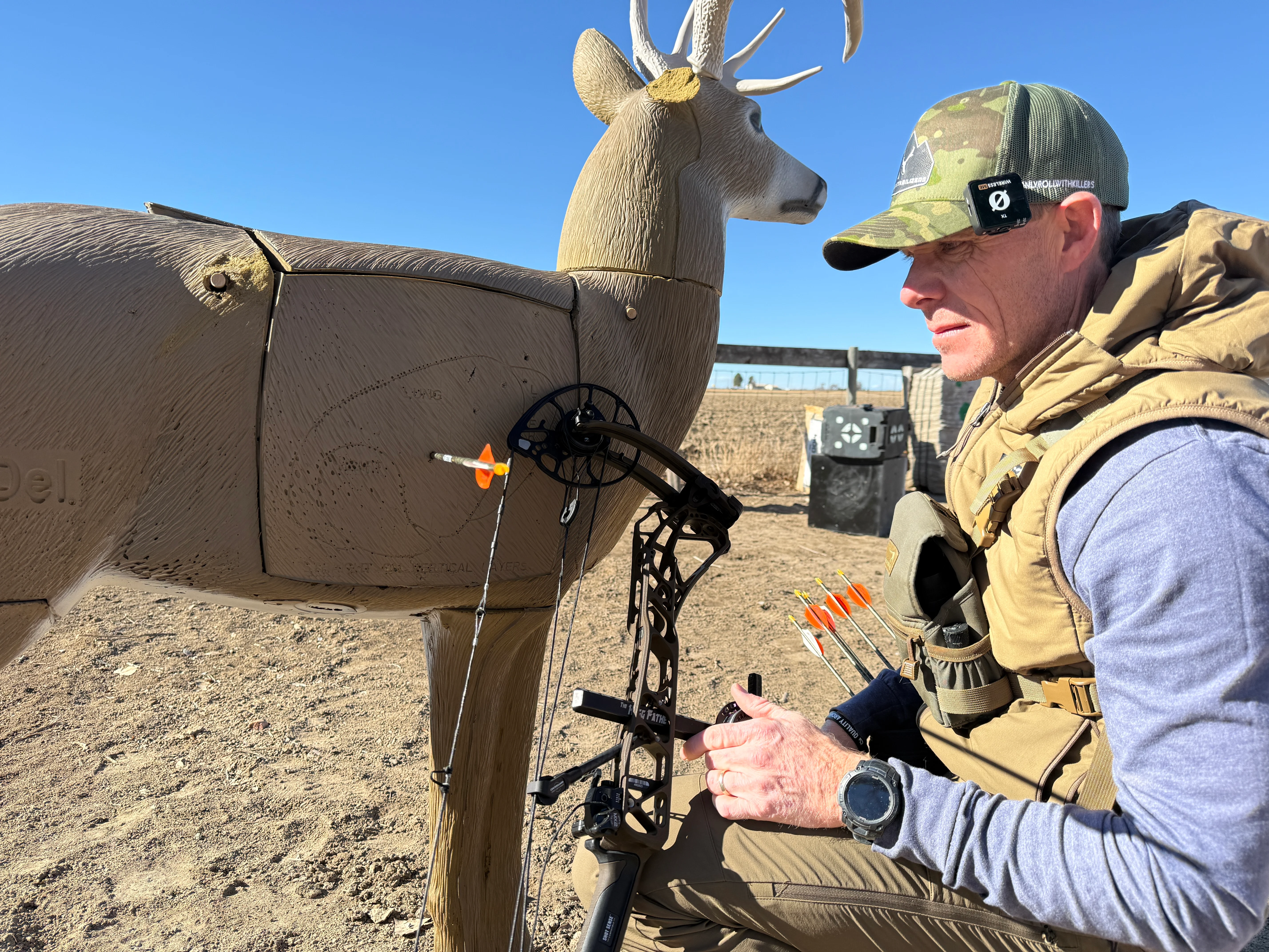 An archery inspects an arrow shot into a 3D deer target. 