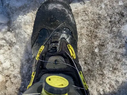 A black fishing boot with a broken BOA lace.