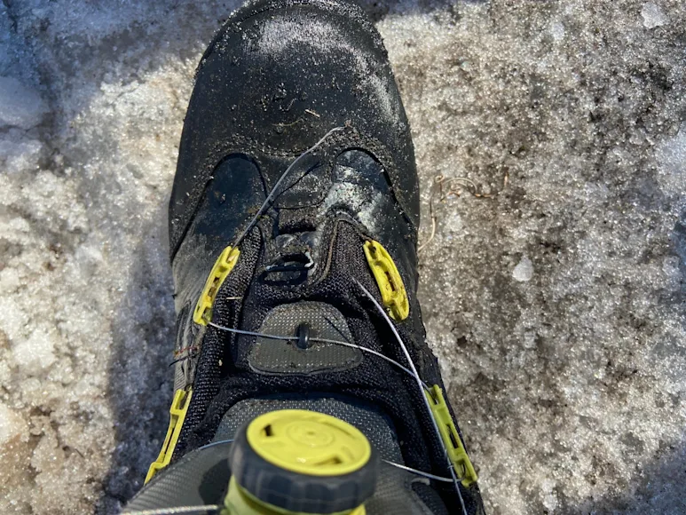 A black fishing boot with a broken BOA lace.