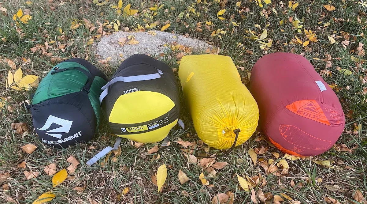 Four 0-degree sleeping bags rolled up on the grass