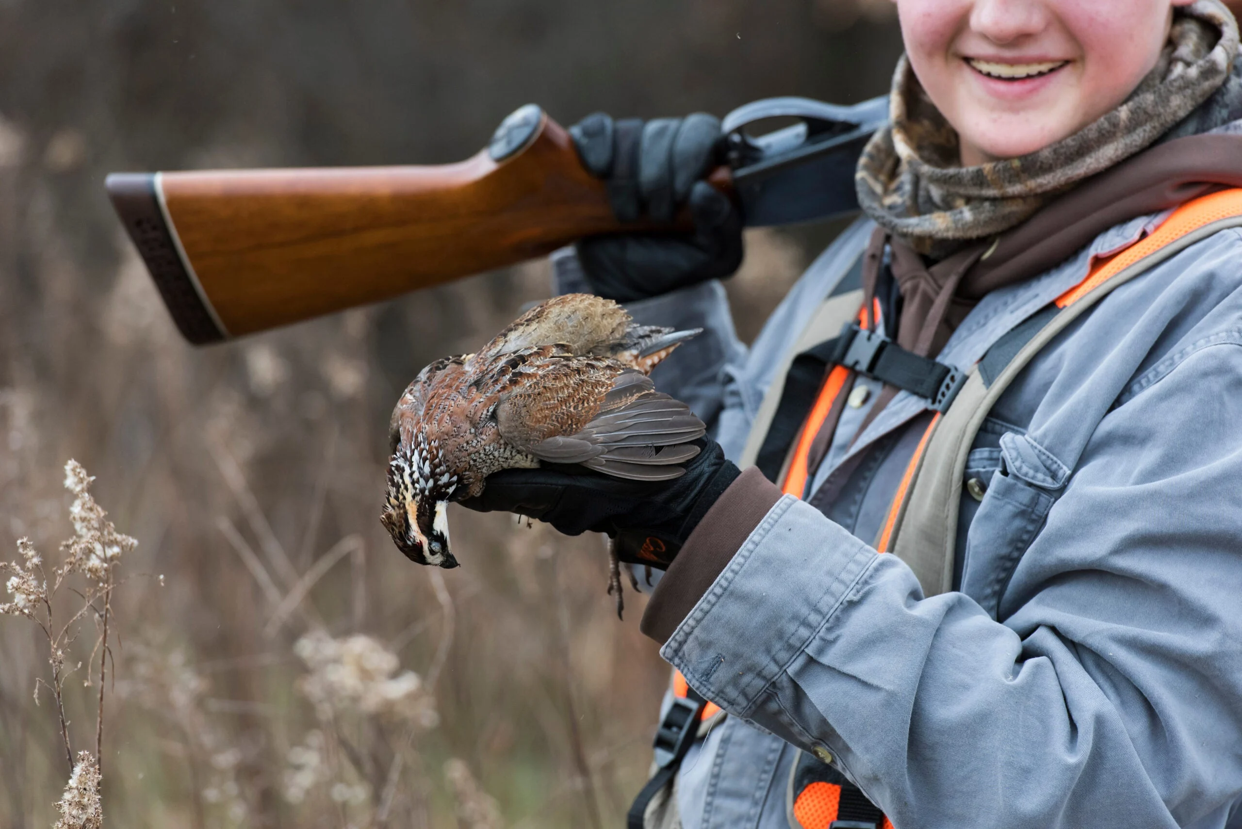 Hunter with shotgun over shoulder shows off a male bobwhite quail