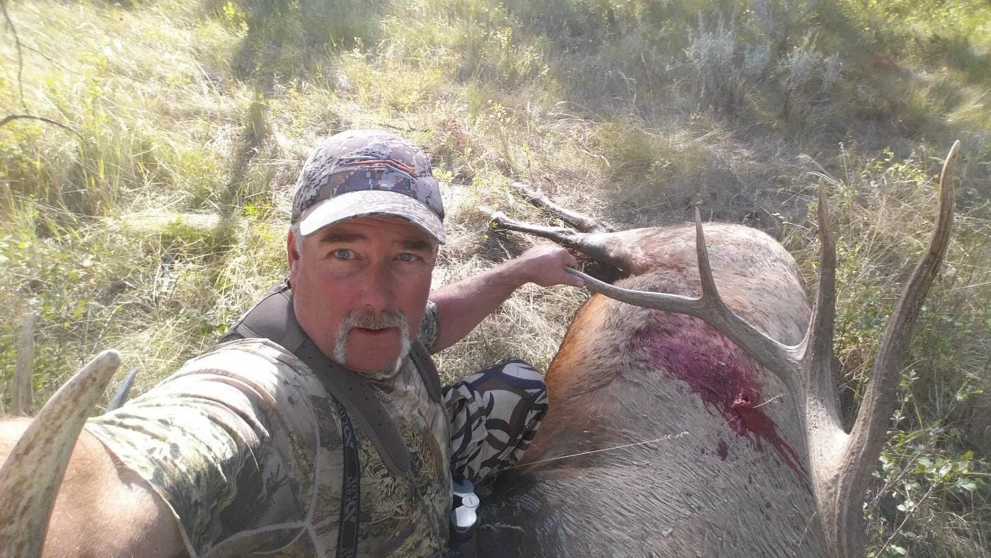 A hunter takes a photo of himself in front of a world record bull elk. 