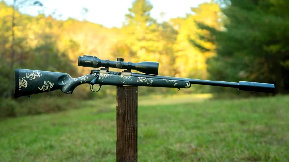 Christensen Ridgeline FFT bolt-action rifle resting on a post in a field with woods in background. 