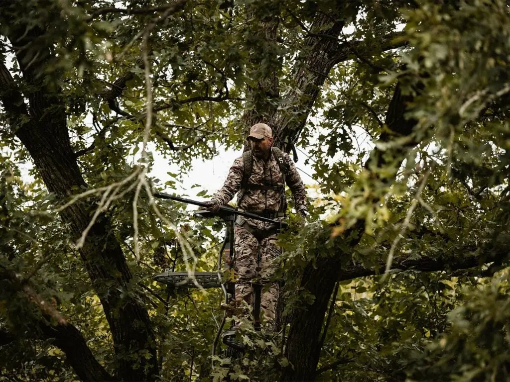 A hunter trims branches to clear shooting lanes