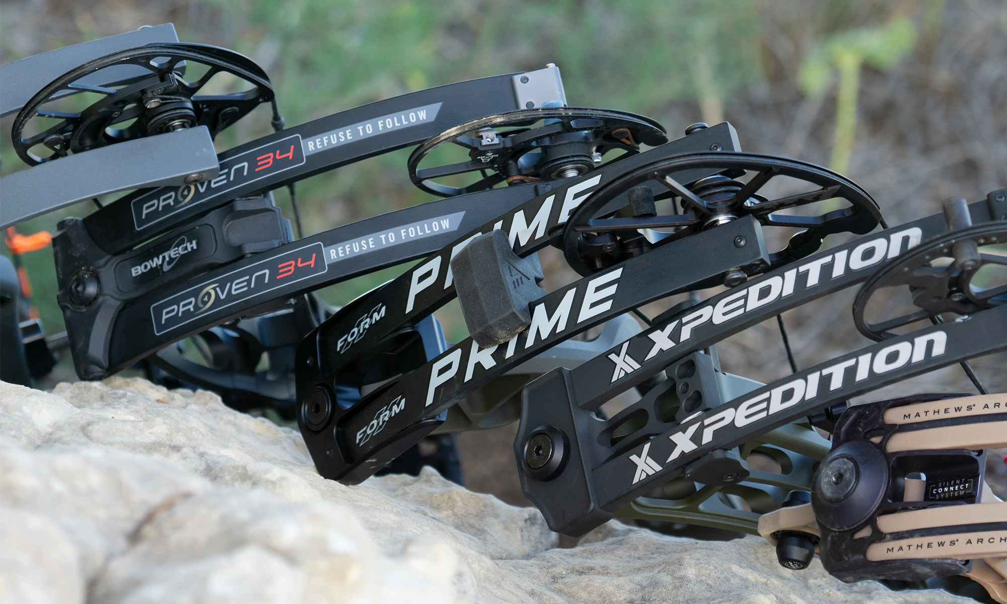 Five of the best compound bows of 2025, laying on a rock. 