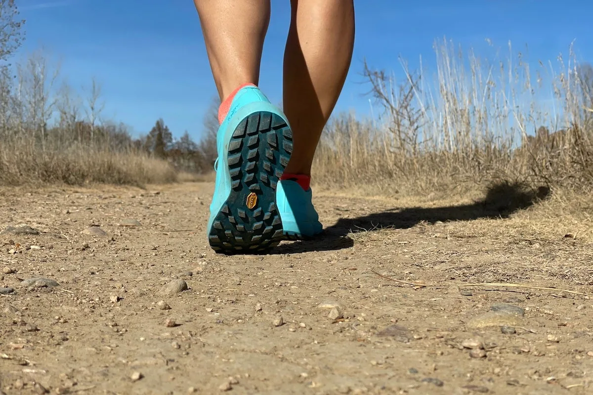 Close-up of bottom of trail running shoes while woman is hiking