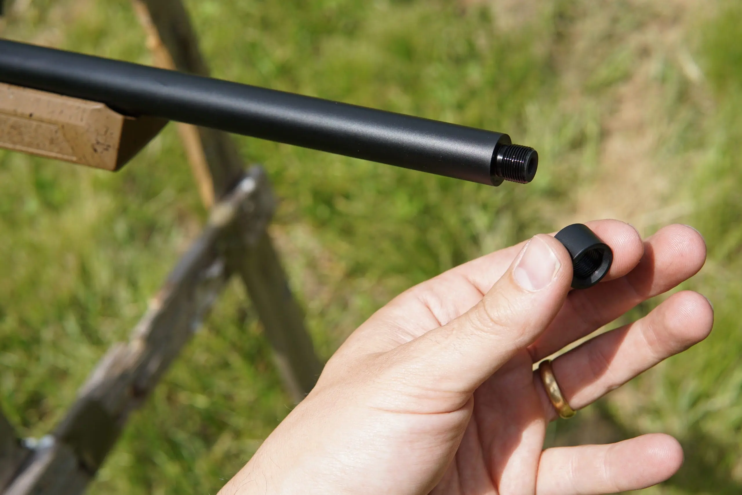A hand holds the removed cap to the Springfield Armory Model 2020 Rimfire's threaded muzzle.