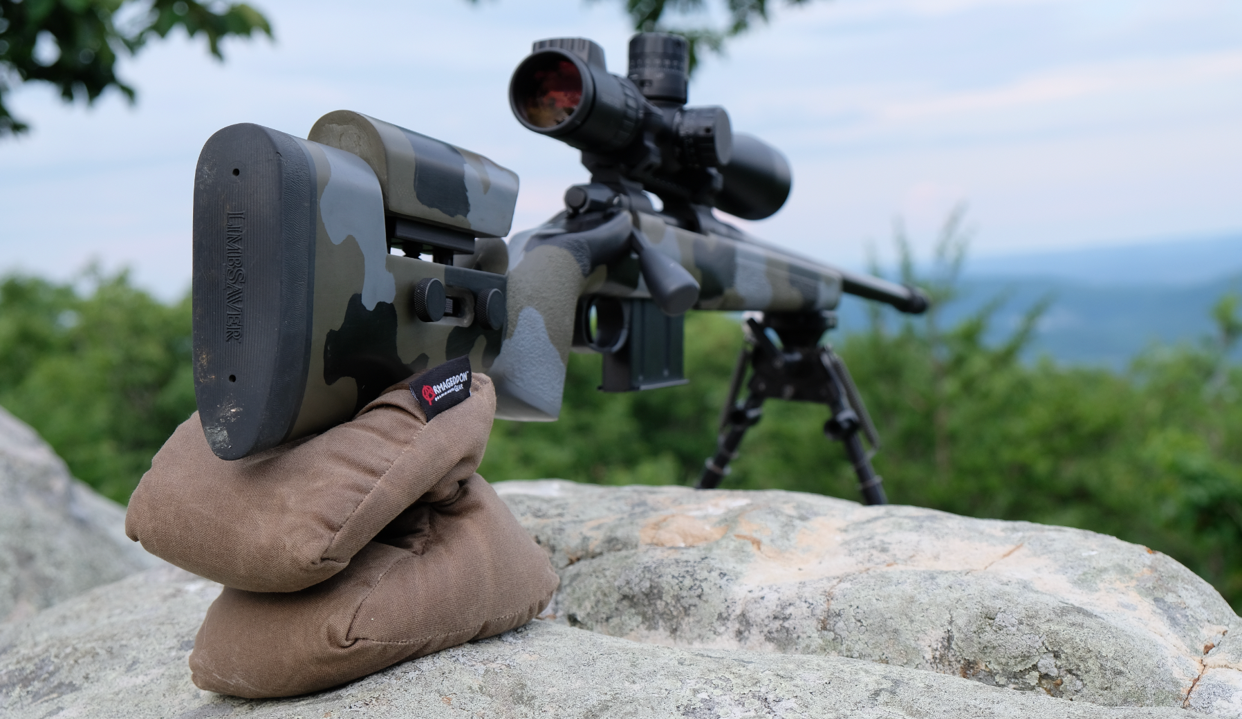 A rifle on a sandbag sitting on a rock.