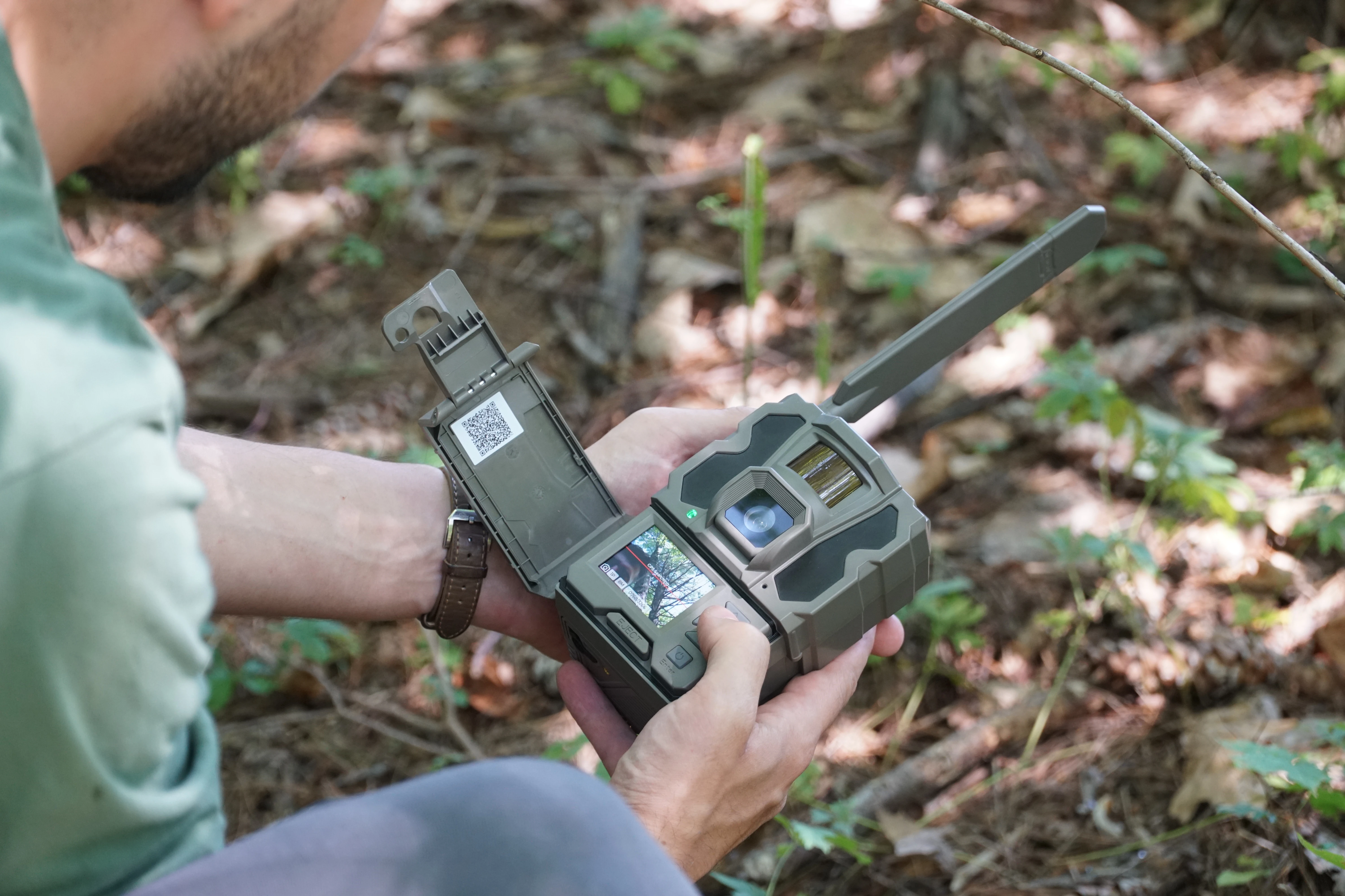 A hunter sets up the new Tactacam Reveal 3.0 trail camera in the woods. 