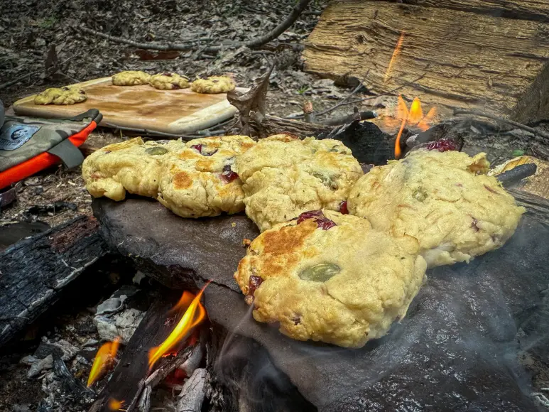 A batch of pine bark cookies bakes on a rock over a fire