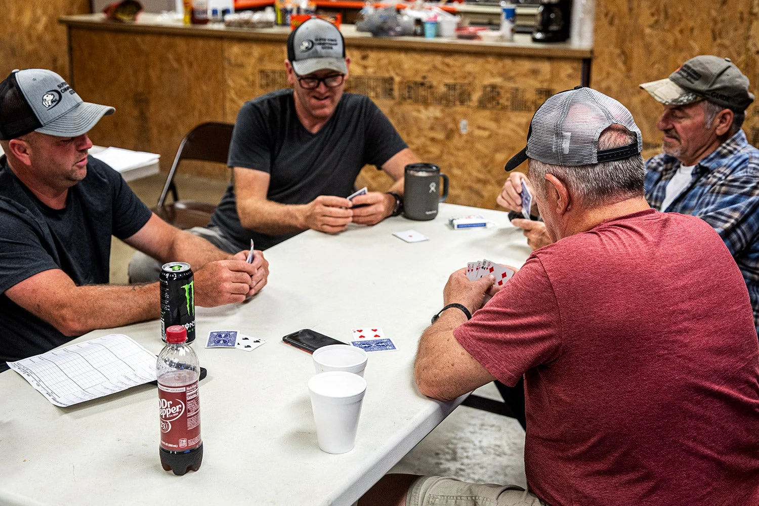 four men playing cards around table