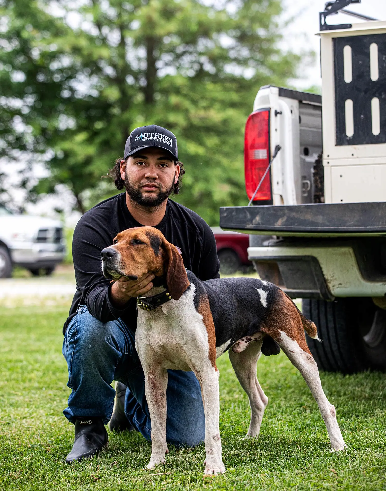 Ronnie Roe Davis and hound Joe pose behind truck