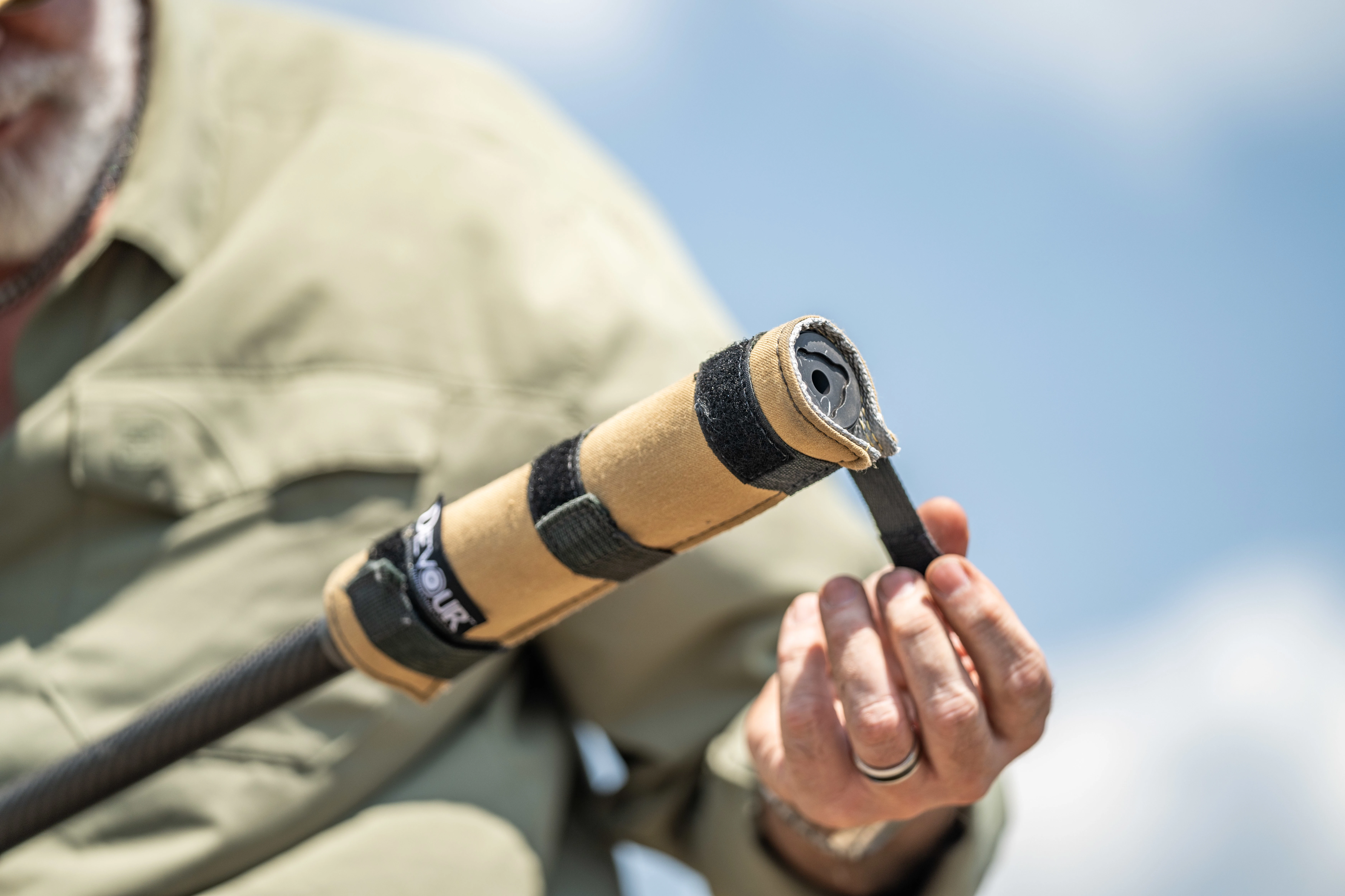 A hunter in a green shirt wraps a case around a suppressor